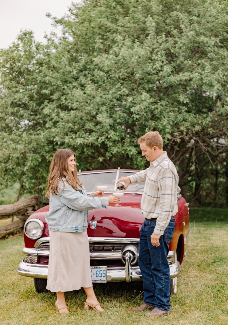 An engaged couple standing by a vintage red truck during an outdoor engagement session in Ottawa