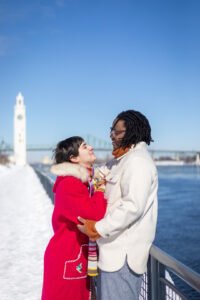 Newly engaged couple Josee and Olivia smiling together against the winter skyline of Montreal.