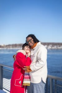 Newly engaged couple Josee and Olivia smiling together against the winter skyline of Montreal.