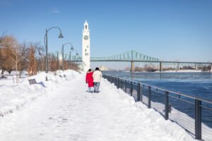Winter landscape of the Old Port Montreal waterfront with a couple walking near the Jacques Cartier Bridge.