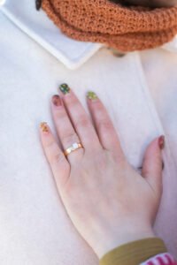 A romantic surprise proposal in the snow at Montréal's Old Port with the white Clock Tower in the background. One person is on one knee while the other reacts with surprise.