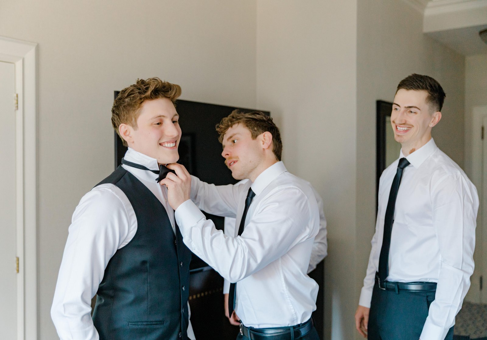 Ottawa wedding photography: groomsmen getting ready, bow tie being tied